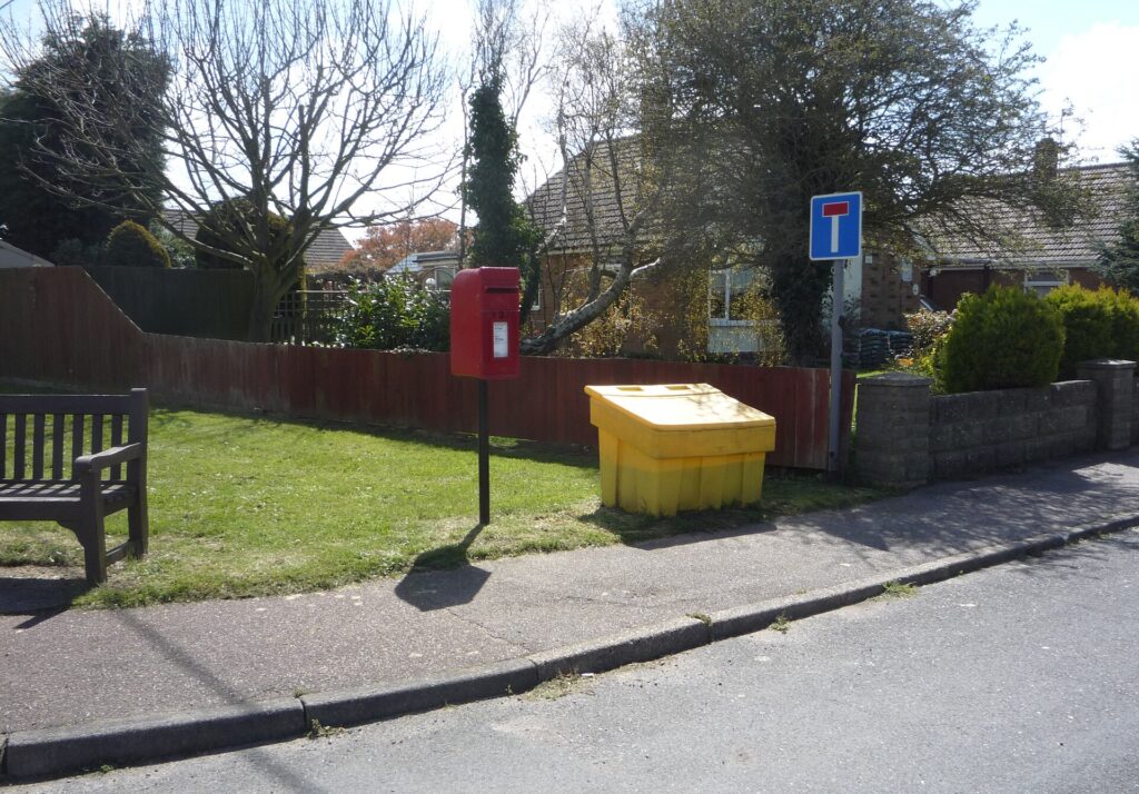 A red post box set into a wall on a quiet English residential road