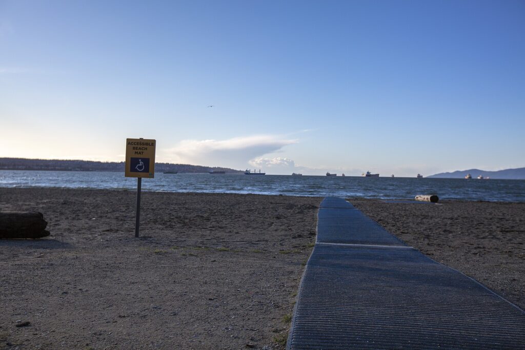 A roll-out access mat stretching across the sand towards the sea