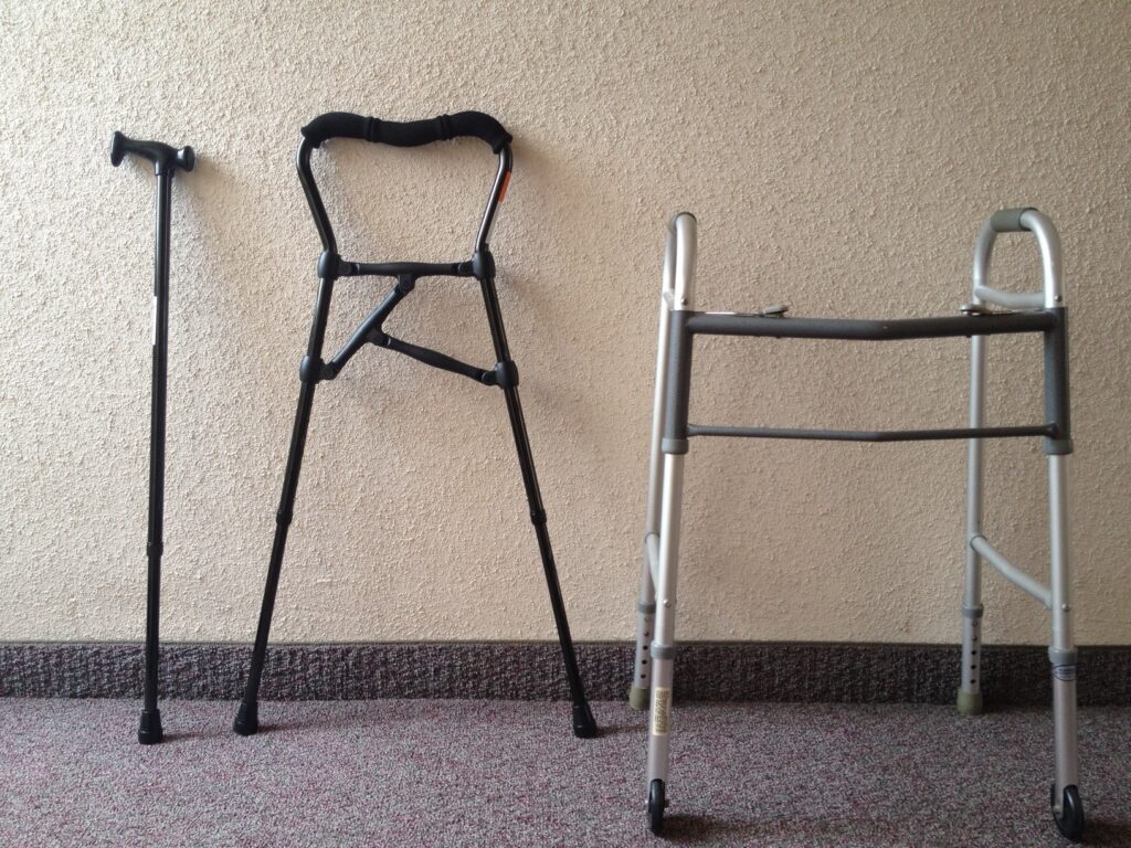 A walking stick, a hybrid walker cane and a walking frame standing side by side