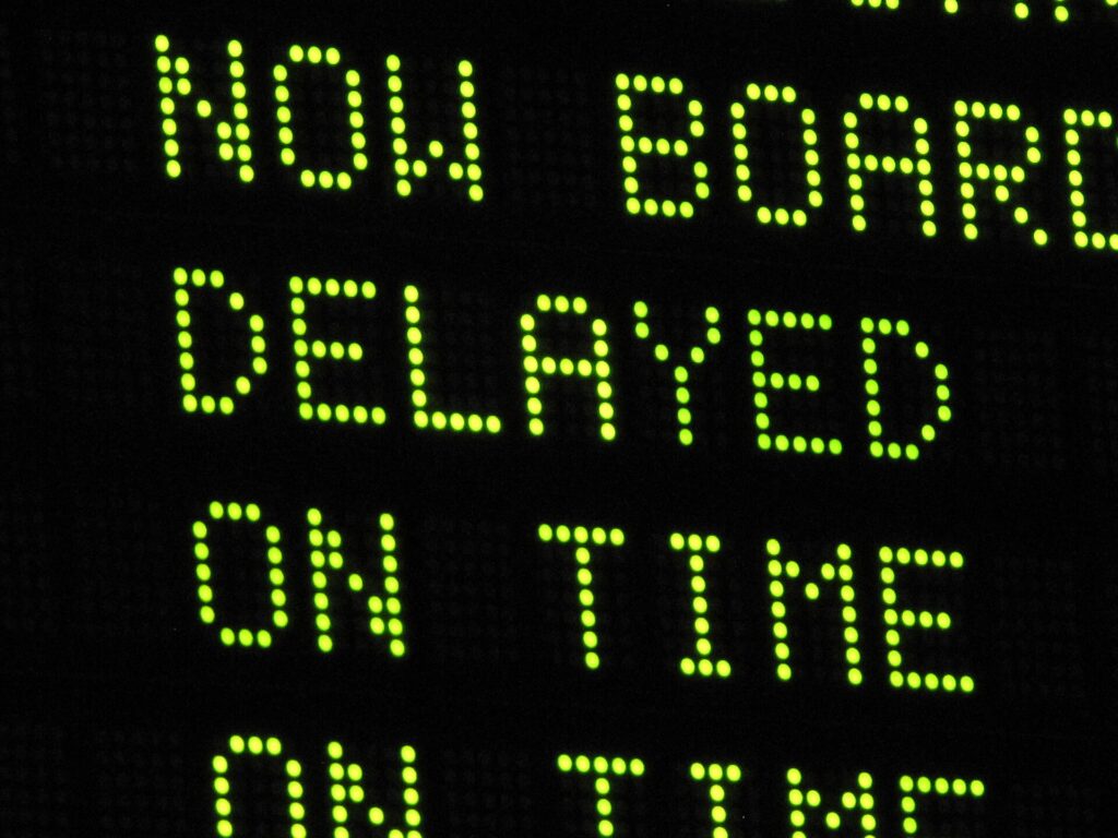 A dot-matrix departure board showing the word Delayed