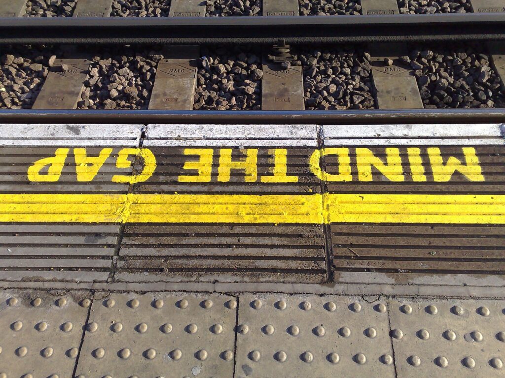 Yellow Mind the Gap lettering painted along the edge of a Tube platform