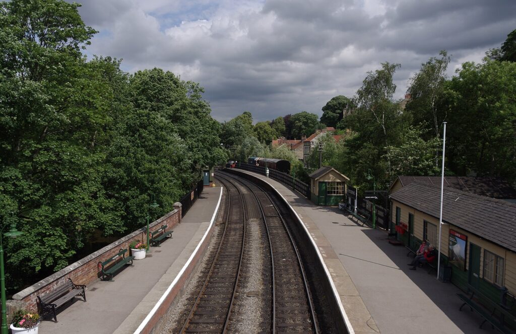 Looking down on Pickering station: two wide, level platforms either side of the track, with benches and station buildings