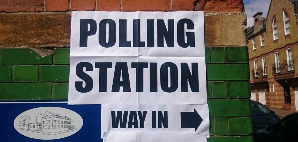 A Polling Station Way In sign with an arrow on a brick wall
