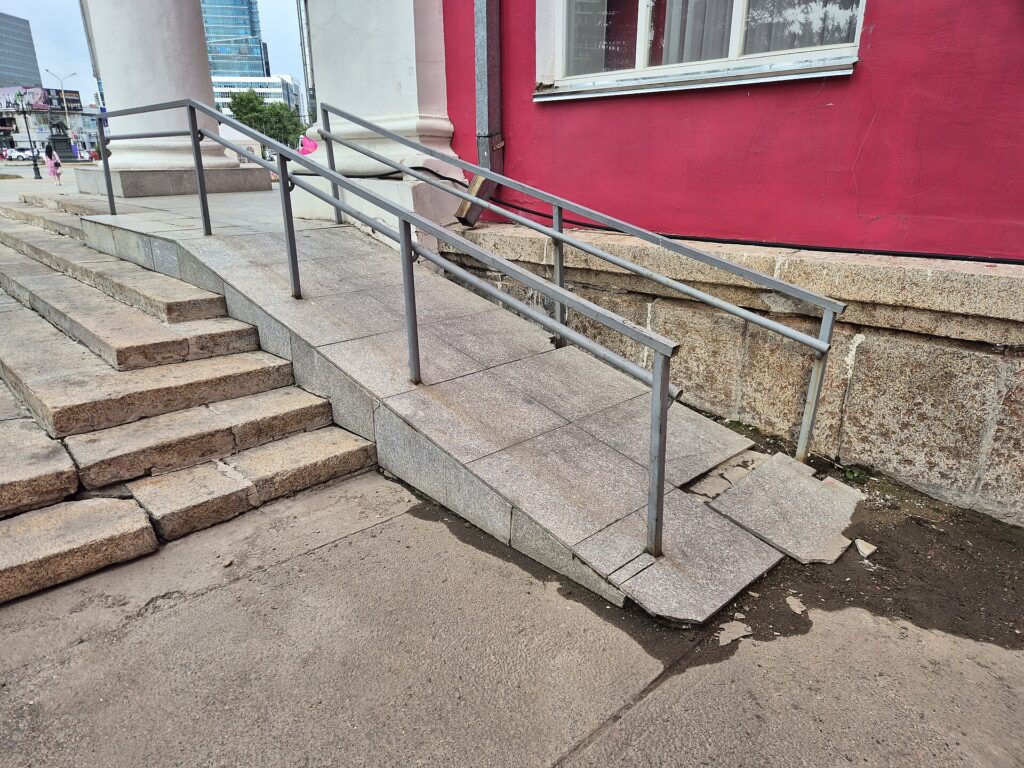 A ramp with handrails built alongside the steps at the entrance of a public building