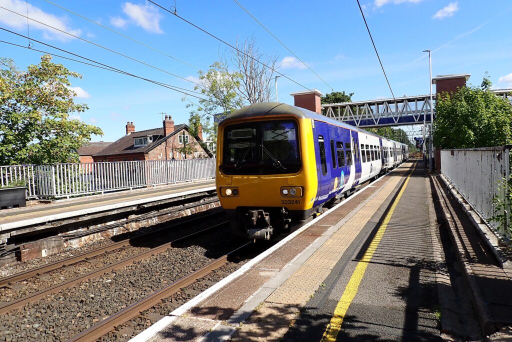 A train arriving at a station platform with passengers waiting